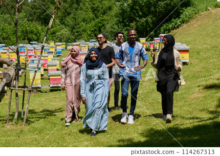 A diverse group of young friends and entrepreneurs explore small honey production businesses in the natural setting of the countryside. 114267313