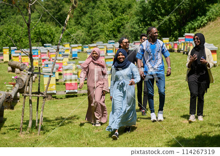 A diverse group of young friends and entrepreneurs explore small honey production businesses in the natural setting of the countryside. 114267319