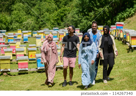 A diverse group of young friends and entrepreneurs explore small honey production businesses in the natural setting of the countryside. 114267340