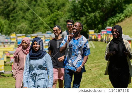 A diverse group of young friends and entrepreneurs explore small honey production businesses in the natural setting of the countryside. 114267358