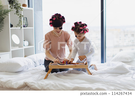 Young woman and cute girl take eye patches from cosmetic table. 114267434