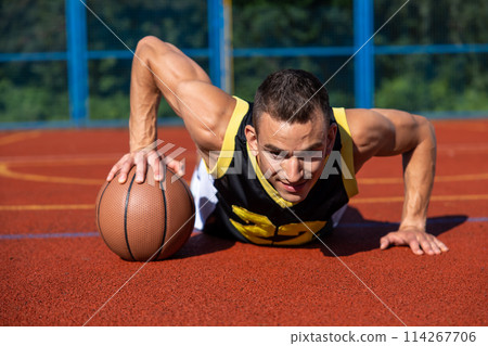 Handsome guy having basketball workout on outdoor summer playground 114267706
