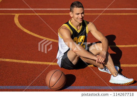 Handsome basketball player sitting on outdoor court 114267718