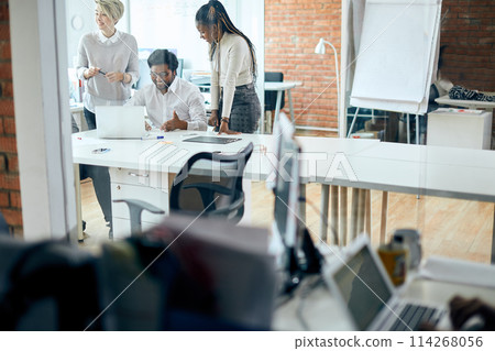 cheerful man and two gorgeous smiling women having fun while working at the office 114268056