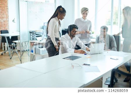 hindoo man is typing the necessary information while his co-workers watching him hindoo man is typing the necessary information while his co-workers watching him 114268059