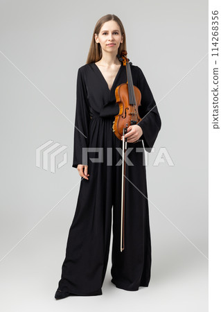 Attractive woman wearing elegant outfit playing violin Attractive woman wearing elegant outfit playing violin 114268356
