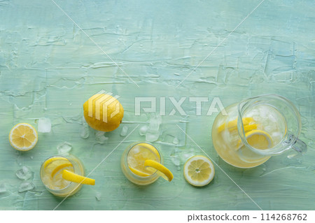 Lemonade. Lemon water drink with ice. Two glasses and a pitcher on blue Lemonade. Lemon water drink with ice. Two glasses and a pitcher on blue 114268762