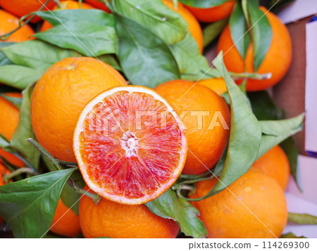A bunch of oranges with one of them cut open 114269300