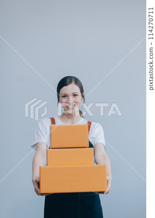 Smiling Asian woman in casual clothes holding a cardboard box mockup while standing against an isolated white background. shipping business concept Smiling Asian woman in casual clothes holding a cardboard box mockup while standing against an isolated white background. shipping business concept 114270711