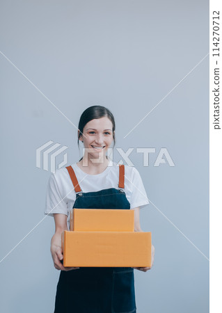 Smiling Asian woman in casual clothes holding a cardboard box mockup while standing against an isolated white background. shipping business concept Smiling Asian woman in casual clothes holding a cardboard box mockup while standing against an isolated white background. shipping business concept 114270712