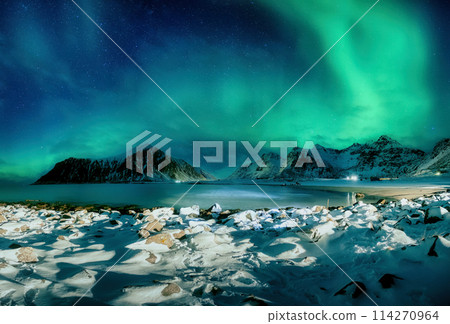 Aurora borealis, Northern lights over snowy mountain on coastline at Skagsanden Beach, Lofoten Islands 114270964