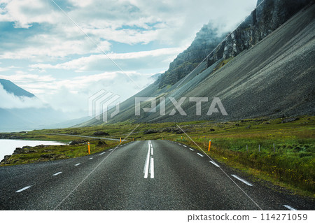 Asphalt road with rugged volcanic mountain in foggy at Iceland 114271059