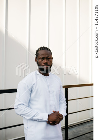 Cheerful male tourist dress in white wear dashiki ethnic smiling at city street on stairs. African American travel model have free time. Copy space Cheerful male tourist dress in white wear dashiki ethnic smiling at city street on stairs. African American travel model have free time. Copy space 114271108