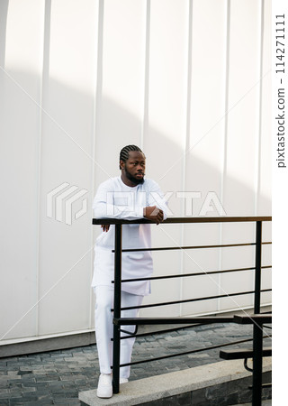 Cheerful male tourist dress in white wear dashiki ethnic smiling at city street on stairs. African American travel model have free time. Copy space Cheerful male tourist dress in white wear dashiki ethnic smiling at city street on stairs. African American travel model have free time. Copy space 114271111