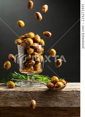 Spicy olives and rosemary twigs on a wooden table. 114271445