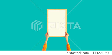 Woman decorating interior, hanging white blank photo frame, wooden picture on wall in new house 114271934