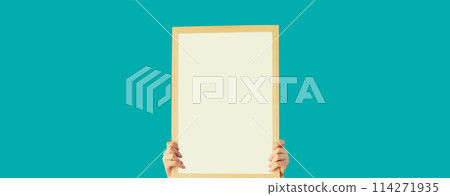 Woman decorating interior, hanging white blank photo frame, wooden picture on wall in new house 114271935
