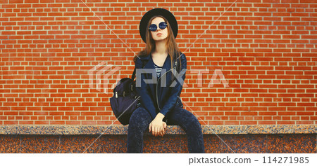 stylish young woman model wearing black round hat, leather jacket in rock style on city street stylish young woman model wearing black round hat, leather jacket in rock style on city street 114271985