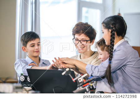 Happy children learn programming using laptops on extracurricular classes 114272398