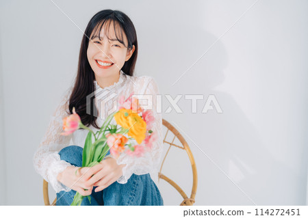 一個女人坐在椅子上，手裡拿著一束花 114272451