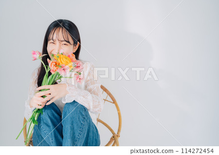 Woman sitting on chair holding a bouquet of flowers Woman sitting on chair holding a bouquet of flowers 114272454