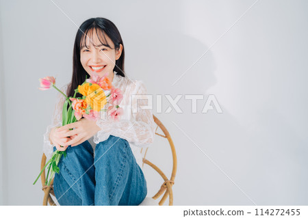 Woman sitting on chair holding a bouquet of flowers Woman sitting on chair holding a bouquet of flowers 114272455