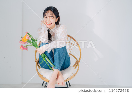 一個女人坐在椅子上，手裡拿著一束花 114272458