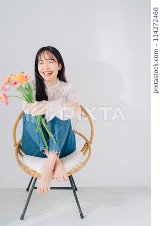 一個女人坐在椅子上，手裡拿著一束花 114272460