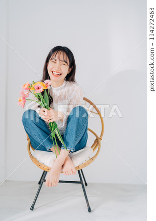 Woman sitting on chair holding a bouquet of flowers Woman sitting on chair holding a bouquet of flowers 114272463