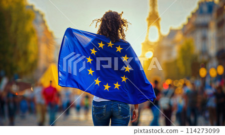 A woman walks down the street of Paris and proudly holds the European Union flag with concentration and determination. 114273099