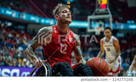 A man in a wheelchair passionately plays basketball on the court, showcasing athleticism and determination. 114273108