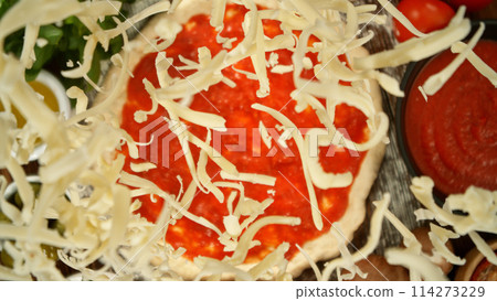 Super slow motion of falling various ingredients on pizza dough with sugo, top down view Super slow motion of falling various ingredients on pizza dough with sugo, top down view 114273229
