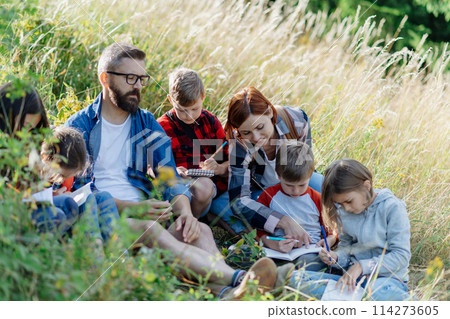 Young students learning about nature, forest ecosystem during biology field teaching class, observing wild plants. Dedicated teachers during outdoor active education. Young students learning about nature, forest ecosystem during biology field teaching class, observing wild plants. Dedicated teachers during outdoor active education. 114273605