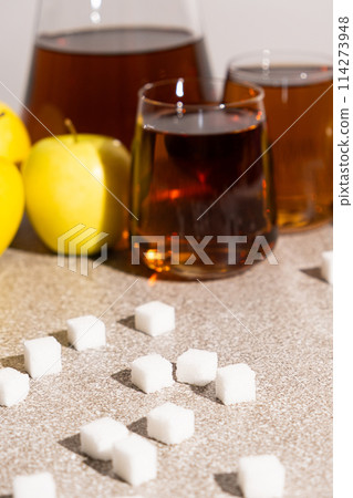 Sugar content in fruit juices. Sugar cubes and glasses of apple juice. Sugar content in fruit juices. Sugar cubes and glasses of apple juice. 114273948