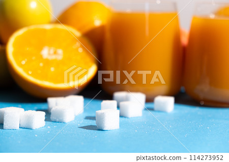 Sugar content in fruit juices. Sugar cubes and glasses of multifruit juice. Sugar content in fruit juices. Sugar cubes and glasses of multifruit juice. 114273952