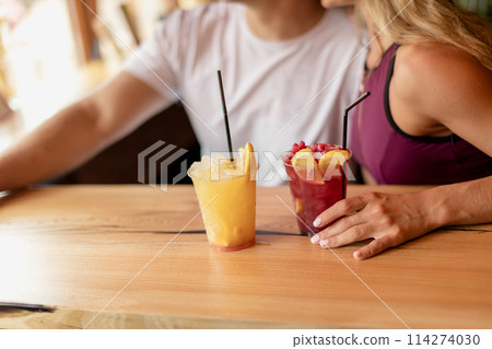 Sportive couple sitting in a cafe enjoying fresh drinks after intensive workout. 114274030