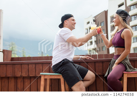 Sportive couple sitting in a cafe enjoying fresh drinks after intensive workout. Sportive couple sitting in a cafe enjoying fresh drinks after intensive workout. 114274038