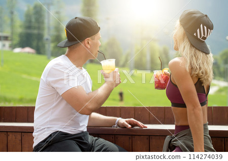 Sportive couple sitting in a cafe enjoying fresh drinks after intensive workout. Sportive couple sitting in a cafe enjoying fresh drinks after intensive workout. 114274039