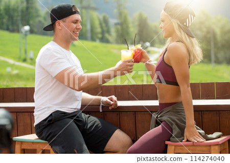 Sportive couple sitting in a cafe enjoying fresh drinks after intensive workout. 114274040