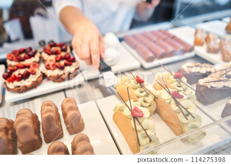 A showcase in a pastry shop with delicious desserts with fresh berries and cream. A variety of cakes covered with chocolate and decorated with pistachio mousse. Delicious pastries in the coffee shop. A showcase in a pastry shop with delicious desserts with fresh berries and cream. A variety of cakes covered with chocolate and decorated with pistachio mousse. Delicious pastries in the coffee shop. 114275398