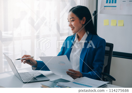 Cheerful business lady working on laptop in office, Asian happy beautiful businesswoman in formal suit work in workplace. Attractive female employee office worker smile. 114275686