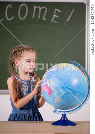 school girl with globe in classroom chalkboard on background school girl with globe in classroom chalkboard on background 114275749