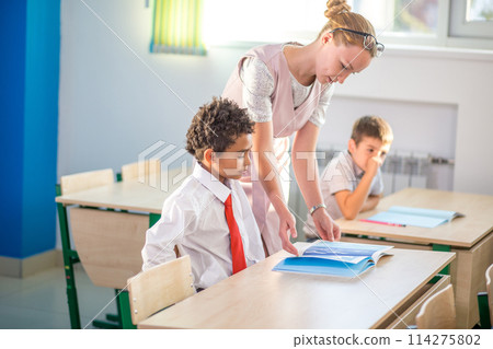 Teacher helping kids with their homework in classroom at school 114275802