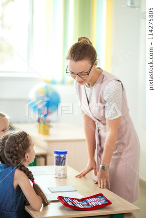 Teacher helping kids with their homework in classroom at school 114275805