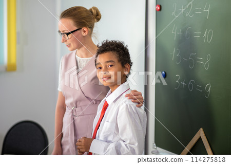 boy solving addition and subtraction on board. schoolboy writing solution of mathematical operation boy solving addition and subtraction on board. schoolboy writing solution of mathematical operation 114275818