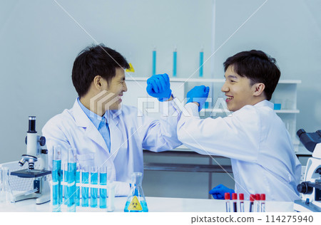 Two asian scientist men fist bump team partner shake hands together. Teamwork Men science chemistry research working success in laboratory. Close up hand pharmaceutical science corporate partnership 114275940
