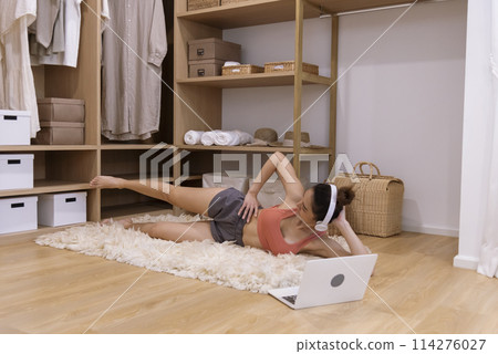 Young Sport Women look at laptop online trainer home fitness workout exercise in living room. Woman using laptop on floor in sportswear arms stretching body weight traning. Healthy lifestyle concept 114276027