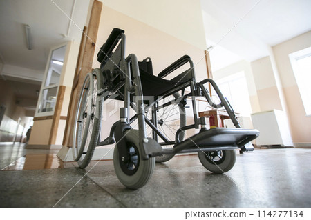 A wheelchair against the background of an empty hospital corridor. A wheelchair against the background of an empty hospital corridor. 114277134