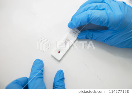 Doctor's hands in gloves hold an express test for coronavirus. Doctor's hands in gloves hold an express test for coronavirus. 114277138