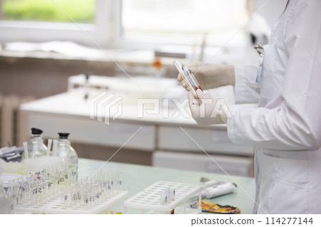 Medical laboratory. The doctor's hands are holding glass test tubes. 114277144